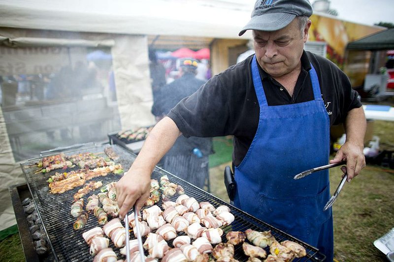 Tom Lyons, with T & J Food Services, turns bacon wrapped quail while manning a grill at the inaugural Little Rock Bacon Fest at the State Fairgrounds on September 13, 2014. Guests of the festival could sample many bacon inspired recipes and attend a bacon eating contest. 