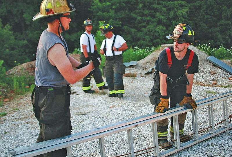 STAFF PHOTO Dan Holtmeyer Round Mountain Chief Shane Wood, left, talks with volunteer Mike Brown on the proper angles, knots and other concerns of using an extendable ladder for a multi-story structure. Brown joined the department over the summer hoping to gain experience and become a more attractive hire for Fayetteville&#8217;s department.