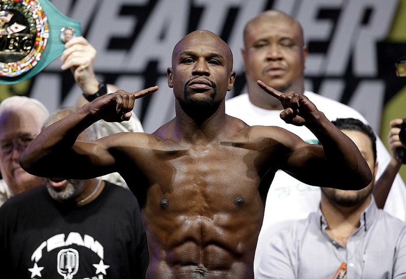 Floyd Mayweather Jr. poses on the scale during a weigh in Friday, Sept. 12, 2014, in Las Vegas. Mayweather Jr. is scheduled to fight Marcos Maidana in a welterweight title fight Saturday in Las Vegas. (AP Photo/John Locher)