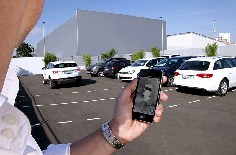 In this undated photo supplied by Valeo, a person activates a self-parking vehicle via a smartphone application. Technology being honed by the French auto parts maker uses a dozen ultrasonic sound-wave sensors, 360-degree cameras and a laser scanner to allow a vehicle to safely park within a few centimeters of other vehicles. (AP Photo/Valeo)