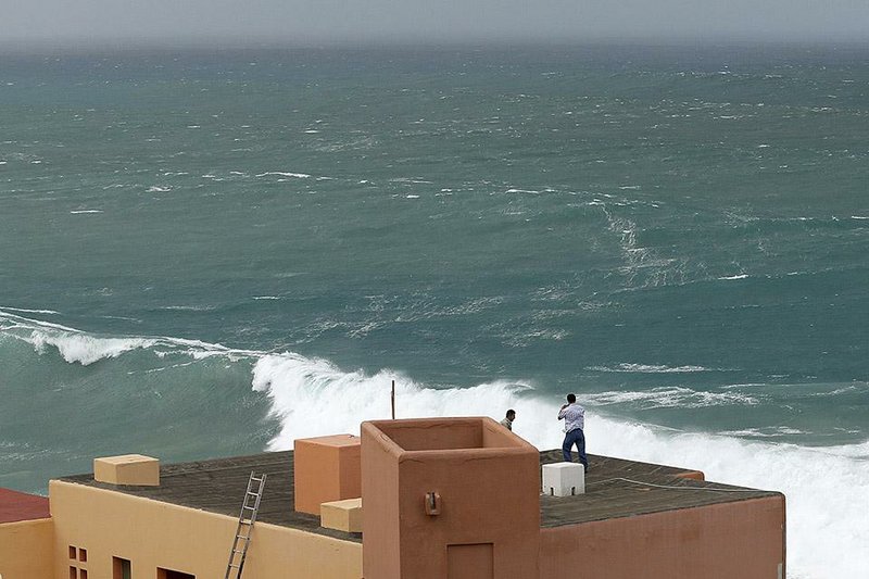 A man takes a photo from the roof of a house at a resort in Los Cabos, Mexico, Sunday, Sept. 14, 2014. Hurricane Odile turned into a Category 4 hurricane and it's expected to make a close brush with the southern portion of Mexico's Baja California peninsula Sunday evening. (AP Photo/Victor R. Caivano)