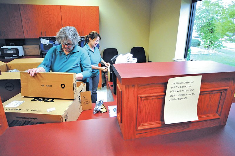 STAFF PHOTO Spencer Tirey Carol Cowell, left, and Cheryle Garrett with the Benton County Revenue Office work Thursday setting up the new satellite office on D Street in Bentonville. The new location opens for business today.