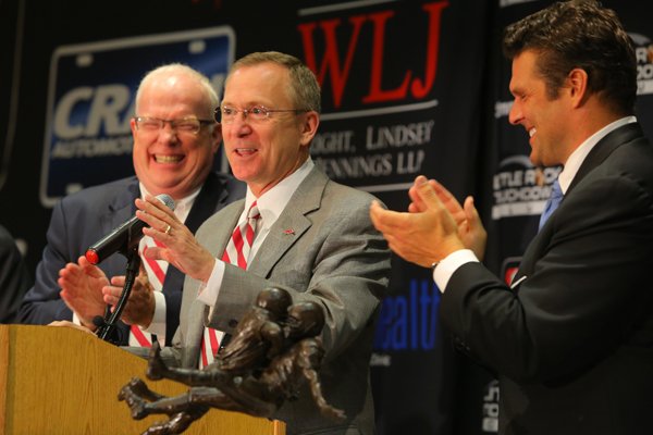 Rex Nelson, left, and David Bazzel, right, applause Arkansas Athletic Director Jeff Long as he steps up to speak at the Little Rock Touchdown Club Monday. 