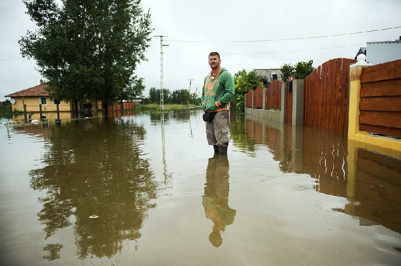 A man stands in water , flooding a street in Siofok, 102 kms southwest of Budapest, Hungary, Monday, Sept. 15, 2014, after three months’ amount of rain fell on the town on Sunday. (AP Photo/MTI, Szilard Koszticsak)