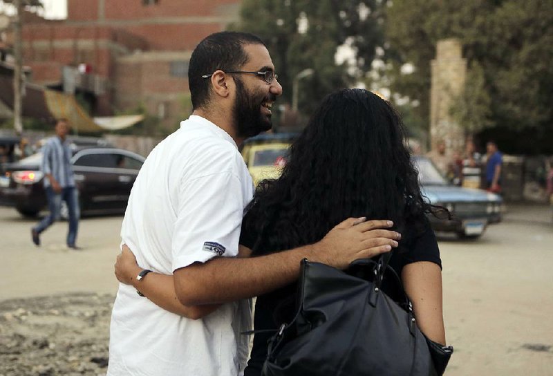 Egypt’s most prominent activist Alaa Abdel-Fattah smiles as he walks with his wife, Manal Hassan, following his release on bail from Tora prison in Cairo, Egypt, Monday, Sept. 15, 2014. Abdel-Fattah is standing retrial after being sentenced to 15 years in prison for violating the country's draconian protest law. The release came after dozens of activists began a hunger strike last month to protest against curbs on public demonstrations and the detention of activists, including some of the leading figures in the 2011 uprising that ended Hosni Mubarak’s nearly three-decade rule. (AP Photo/Amr Nabil)