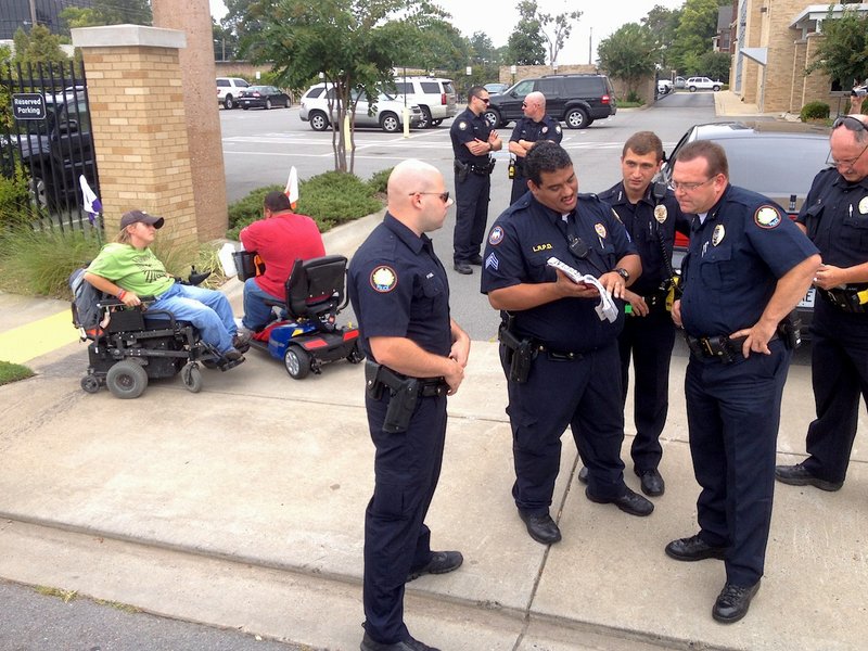 Little Rock police work to determine the appropriate charge before arresting ADAPT protesters Tuesday afternoon on Capital Avenue. Police said four of the demonstrators refused orders to leave the street.