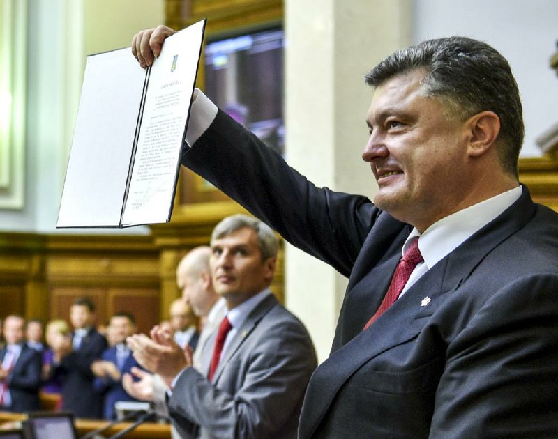 Ukrainian President Petro Poroshenko waves a copy of an agreement ratified by his country’s parliament Tuesday in Kiev strengthening economic and political ties with the European Union. Poroshenko called the vote a “first but very decisive step” toward bringing Ukraine fully into the European Union. 