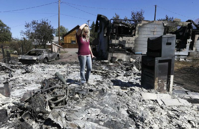 Kate Stonecypher, 22, walks through the burned remains of her garage Tuesday in Weed, Calif.