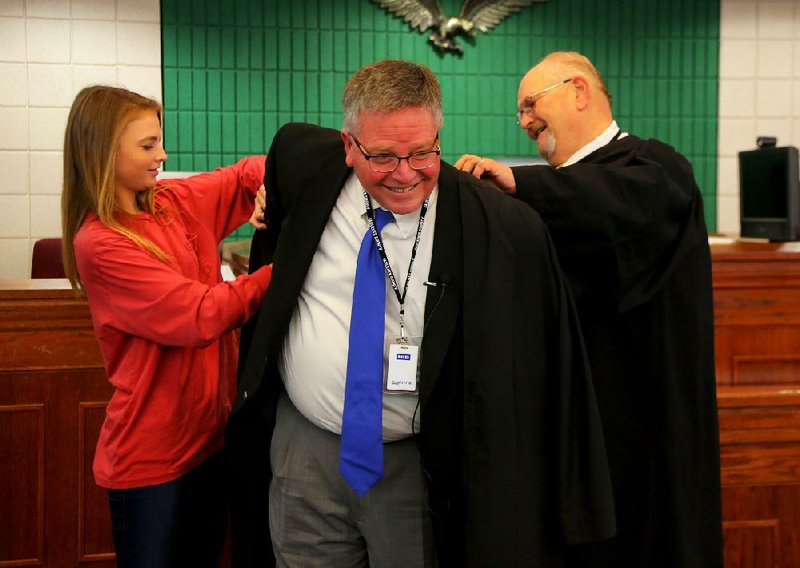 Sarah Murphy (left) helps Judge Ed Clawson (right) place a robe on her father, former Conway City Attorney Mike Murphy, after he was sworn in Tuesday as a circuit judge in Conway, replacing Michael Maggio.