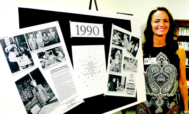 Tom A. Throne/The Weekly Vista Nancy Galbraith, program specialist at the Schmieding Center for Senior Health and Education in Bella Vista, stands by one of the picture boards that contains information and photos of the first Senior Health Fair in 1990.