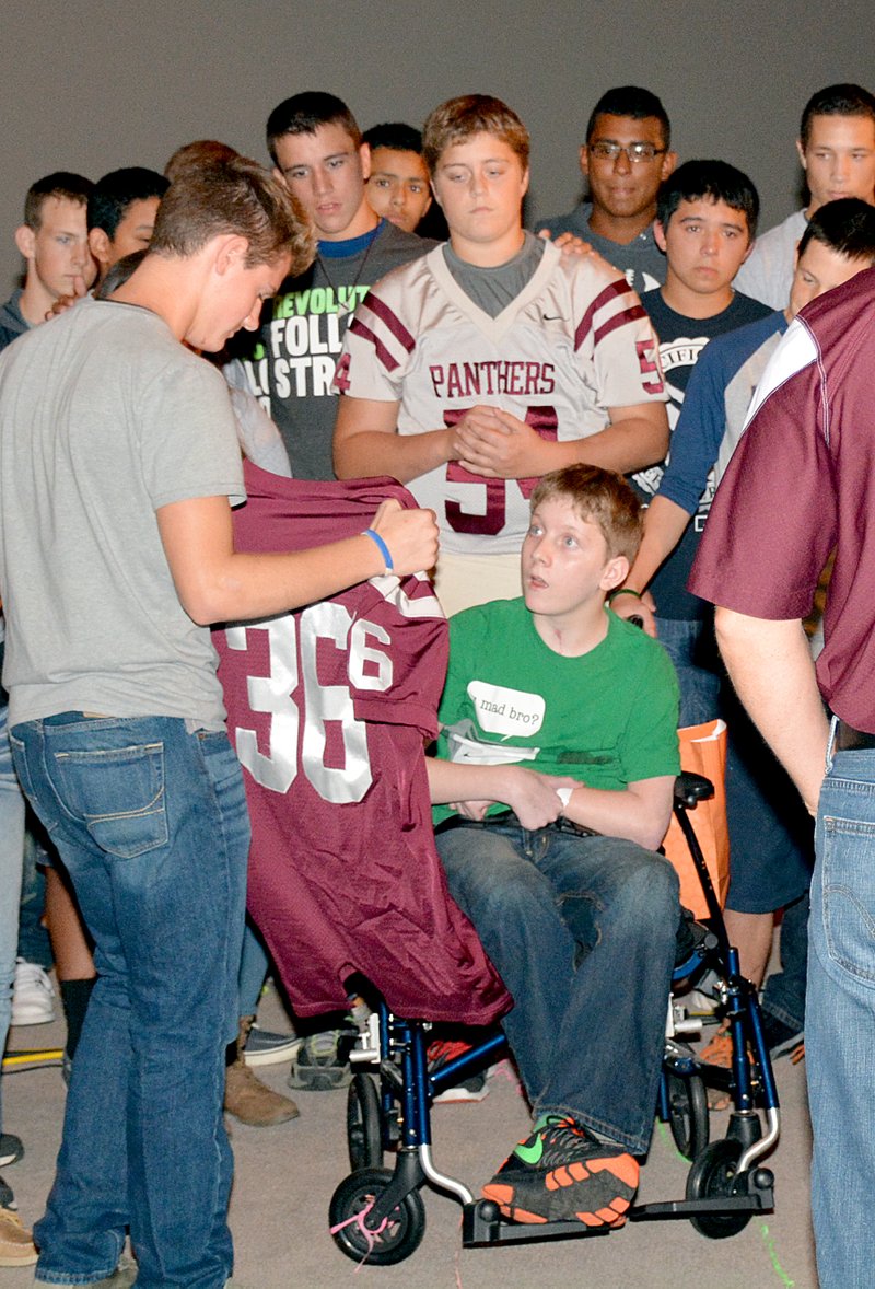 Janelle Jessen/Herald-Leader Seth Hufford presented a football jersey to Clay Walker on behalf of the ninth-grade football team Saturday. Walker would have played on the team this year had he not been in a car accident in March. The team made him an honorary member.