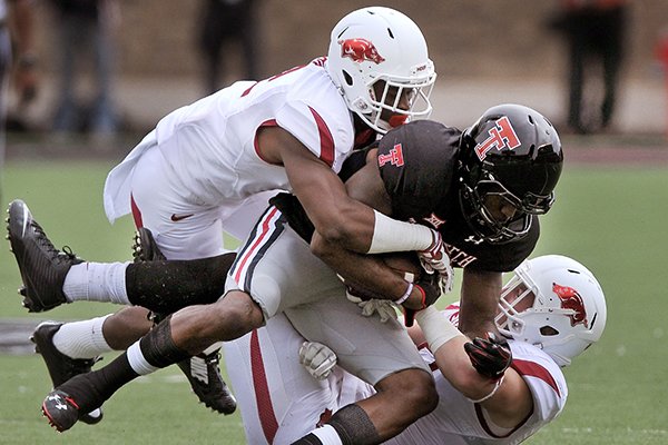 Arkansas cornerback D.J. Dean, left, and middle linebacker Brooks Ellis tackle Texas Tech wide receiver Reginald Davis in the first quarter of a game at Jones AT&T Stadium in Lubbock, Texas on Saturday, Sept. 13, 2014. 