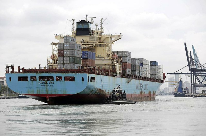 A tugboat guides a Maersk Line container ship into the Port of Miami in May. The U.S. trade deficit fell to $98.5 billion in the second quarter, the Commerce Department reported Wednesday.