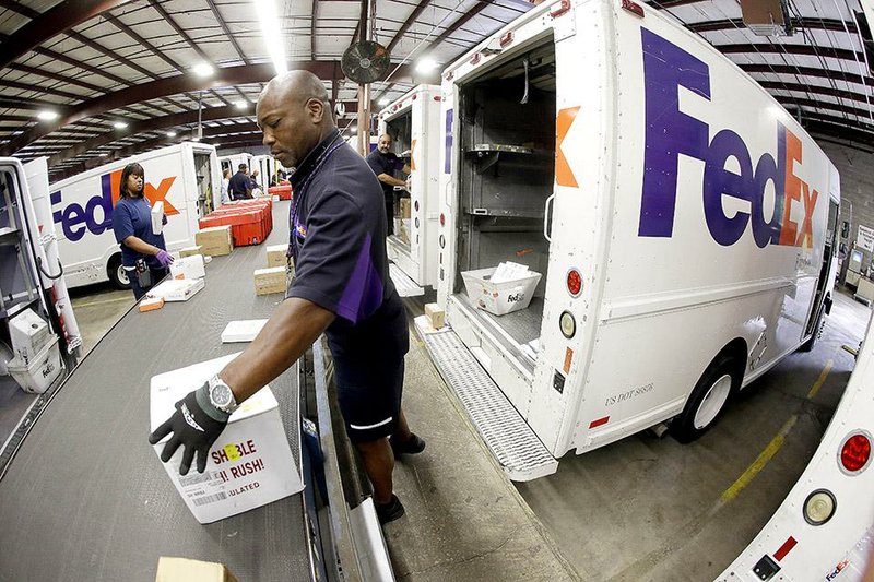 A FedEx driver loads packages onto his truck at a FedEx Express station in Nashville, Tenn., in July. The company Wednesday reported a quarterly profit of $606 million.