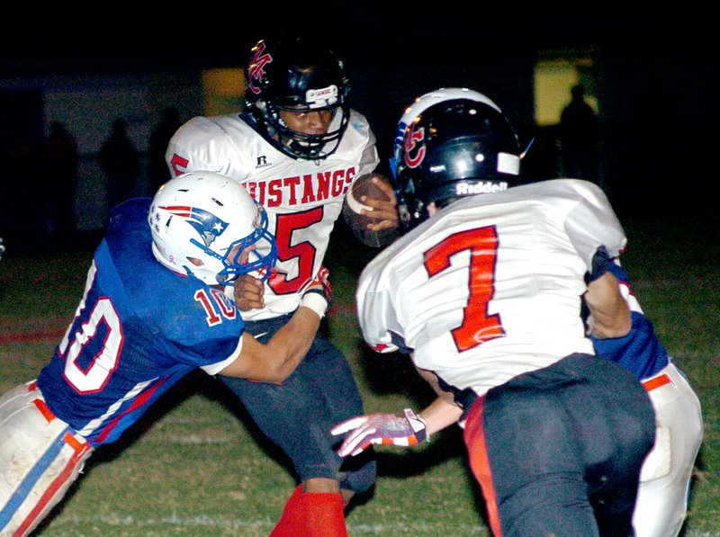 RICK PECK MCDONALD COUNTY PRESS McDonald County&#8217;s Lavante Jackson drags East Newton&#8217;s Drew Williams for a short game while teammate Josh Kinser (7) throws a block during the Mustangs&#8217; 21-6 win Friday night at East Newton High School.