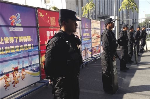 Armed policemen stand guard near Xinjiang's tourism advertisement boards, which authority used to block off the road heading to Urumqi People's Intermediate Court in Urumqi, China's northwestern region of Xinjiang Wednesday, Sept. 17, 2014. Ilham Tohti, a scholar from China's Muslim Uighur minority community who often criticized the country's ethnic policies is set to go on trial on separatism charges in the country's far western region of Xinjiang.