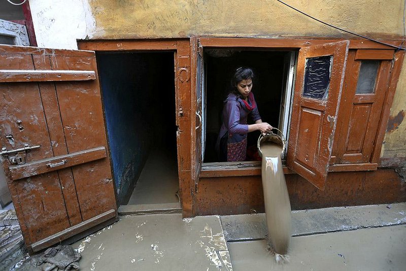 A Kashmiri woman drains muddy water  from her flood damaged house in Srinagar, Indian-controlled Kashmir, Thursday, Sept.18, 2014. The floods engulfed much of Kashmir two weeks ago, leaving hundreds of thousands of people homeless in both the Indian- and Pakistani-administered areas of the disputed territory. (AP Photo/Dar Yasin)