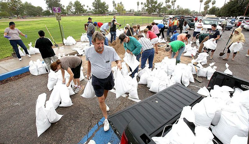 Barton Morse carries sand bags to his truck at Fort Lowell Park for delivery to a friend Wednesday as the remnants of Hurricane Odile makes their way into Tucson, Ariz. Odile was downgraded to a tropical depression when rain started falling across much of the state.