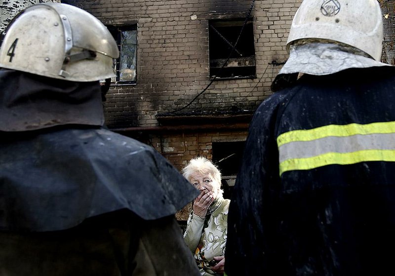 Firefighters check on a woman Wednesday outside an apartment building that was damaged by artillery fire in Donetsk in eastern Ukraine.