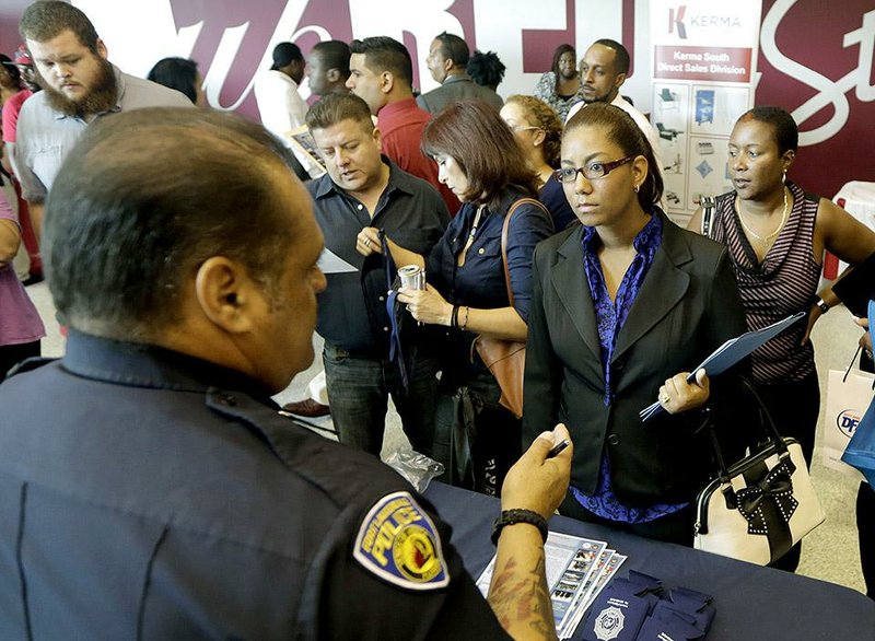 In this photo taken Tuesday, Aug. 19, 2014, job seeker Migdalia Feliz, of Miramar, Fla., third from right, listens to detective William DeJeus, left, of the Fort Lauderdale Police Department, at a job fair in Sunrise. Fla. The Labor Department reports on the number of people who applied for unemployment benefits last week on Thursday, Sept. 18, 2014. (AP Photo/Alan Diaz)