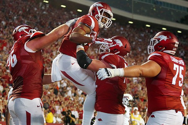 Arkansas offensive tackle Frank Ragnow, right, lifts wide receiver Jared Cornelius as they celebrate Cornelius' touchdown against Northern Illinois in the second quarter of an NCAA college football game in Fayetteville.  Saturday, Sept. 20, 2014.
