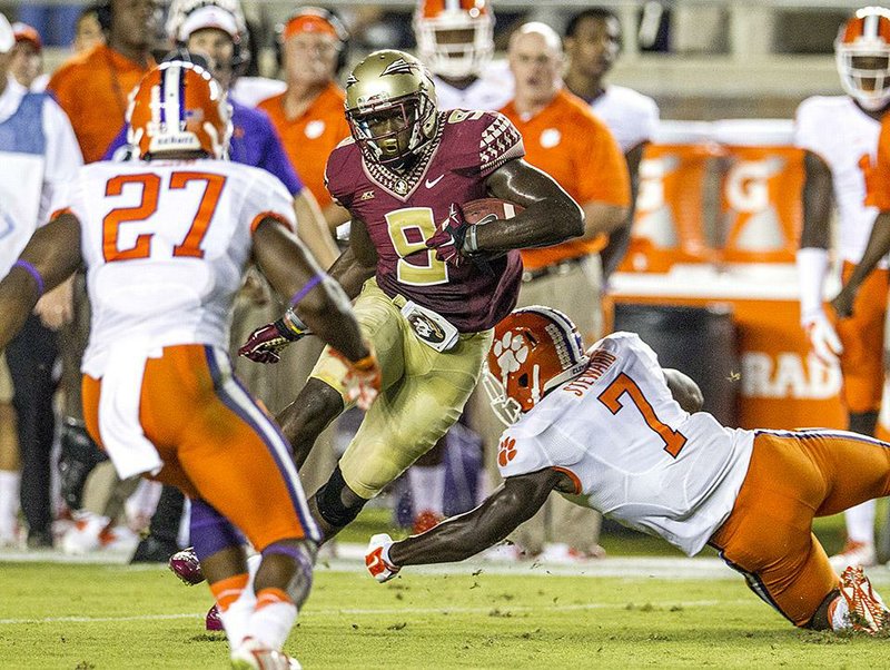 Florida State running back Karlos Williams (center) makes a move between Clemson’s Robert Smith (left) and Tony Stewart for a 27-yard gain during the first half of the top-ranked Seminoles’ 23-17 overtime victory over the No. 22 Tigers on Saturday in Tallahassee, Fla.