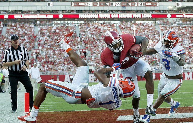 Alabama wide receiver Amari Cooper (9) scores a touchdown against Florida cornerback Vernon Hargreaves III (1) and linebacker Antonio Morrison (3) during the second half of Saturday’s game in Tuscaloosa, Ala. Cooper scored three touchdowns as Alabama won 42-21. 