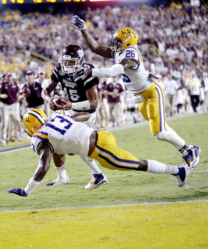 Mississippi State quarterback Dak Prescott (15) dives into the end zone over LSU cornerback Dwayne Thomas (13) and safety Ronald Martin (26) on a 56 yard touchdown run Saturday in Baton Rouge.