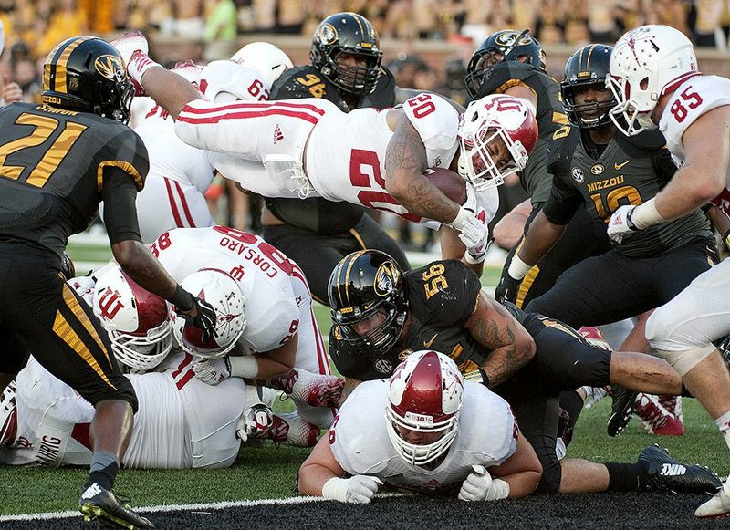 Indiana running back D’Angelo Roberts (center) dives over several players as he scores the game-winning touchdown Saturday, in Columbia, Mo. Indiana upset Missouri 31-27.