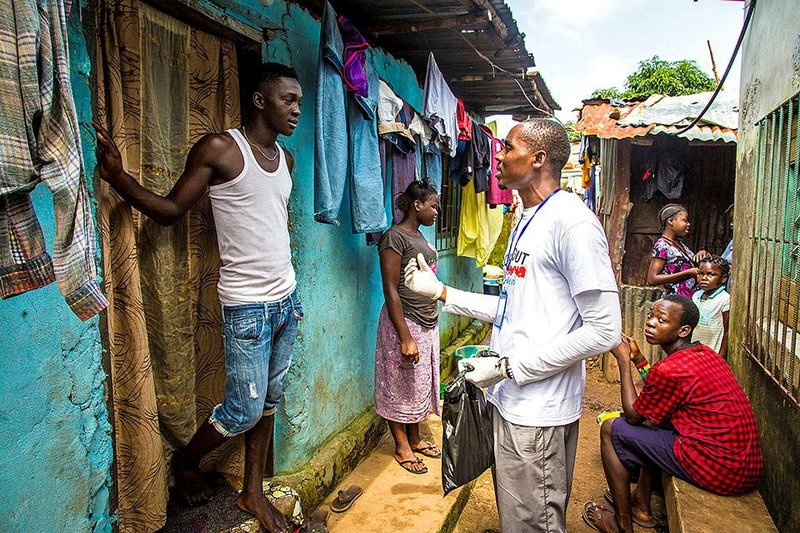A health worker volunteer talks with a resident on how to prevent and identify the Ebola virus in others, and distributes bars of soap in Freetown, Sierra Leone, Saturday, Sept. 20, 2014. Thousands of health workers began knocking on doors across Sierra Leone on Friday in search of hidden Ebola cases with the entire West African nation locked down in their homes for three days in an unprecedented effort to combat the deadly disease. (AP Photo/Michael Duff)
