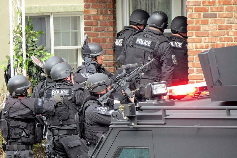 FILE - In this April 22, 2014, file phot, Nassau County police officers enter a home in Long Beach, N.Y., in search of an armed killer, based on a phone call that turned out to be a hoax. Authorities say the dangerous and costly prank known as “swatting", is becoming increasingly popular among people who play combat games over live video feeds while thousands of people watch. Authorities estimated they spent $100,000 to send more than 60 officers to the Long Beach, Long Island swatting hoax.  (AP Photo/Newsday, Jim Staubitser, File)