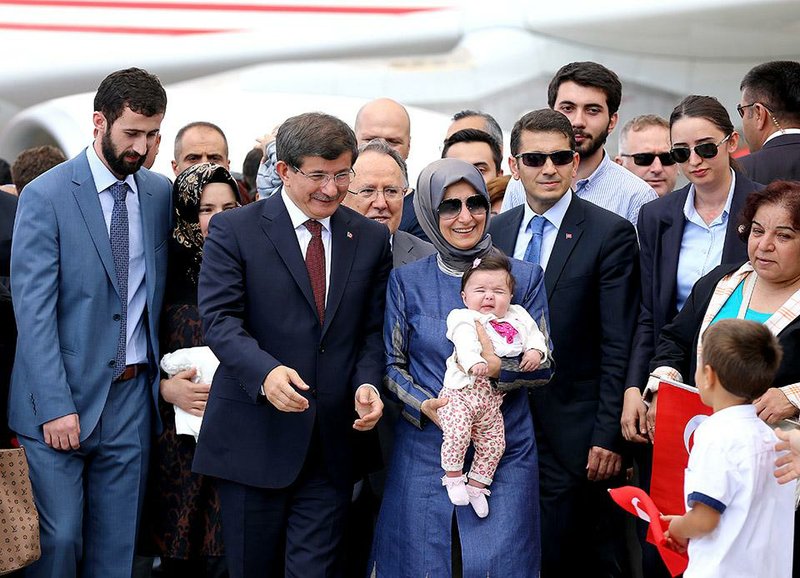 Turkish Prime Minister Ahmet Davutoglu, center left, stands with freed hostages at the airport in Ankara, Turkey, Saturday, Sept. 20, 2014. Dozens of Turkish hostages seized by Islamic militants in Iraq three months ago were freed and safely returned to Turkey on Saturday ending Turkey’s most serious hostage crisis. The 49 hostages were captured from the Turkish Consulate in Mosul, Iraq on June 11, when the Islamic State group overran the city in its surge to seize large swaths of Iraq and Syria. (AP Photo)