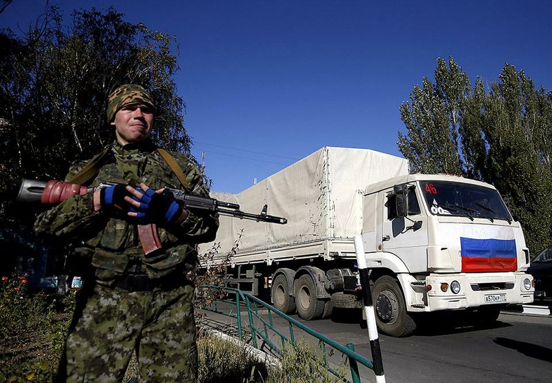 A pro-Russian rebel guards convoy of white trucks with humanitarian aid from Russia in the town of Donetsk, eastern Ukraine, Saturday, Sept. 20, 2014. Negotiators in Ukrainian peace talks agreed early Saturday to create a buffer zone to separate government troops and pro-Russian militants and withdraw heavy weapons and foreign fighters in order to ensure a stable truce in eastern Ukraine. (AP Photo/Darko Vojinovic)