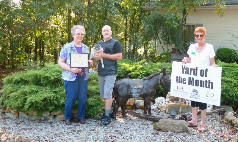 Submitted photo ENHANCED YARD WORK: Congratulations to the Gary and Lillian Letson, left, for creating an outstanding garden. In appreciation and recognition of their gardening efforts, they were presented with a certificate of appreciation from the Garland County Master Gardeners by master gardener Val Nuckels, the Yard of the Month sign is posted on the golf course side of their garden for the month of September and they receive a one-year membership to Garvan Woodland Gardens.