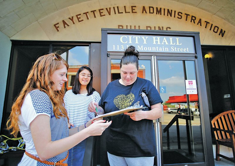 STAFF PHOTO DAVID GOTTSCHALK Volunteers Meagan Forsyth, from left, from Combs, and Hannah Reber of Fayetteville collect a signature from Amanda Autry on a petition to force a special election on the Civil Rights Administration ordinance the Fayetteville City Council approved Aug. 20