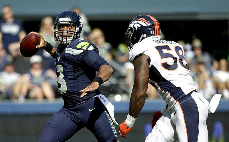 Seattle Seahawks quarterback Russell Wilson passes under pressure from Denver Broncos outside linebacker Von Miller (58) during the first half of an NFL football game, Sunday, Sept. 21, 2014, in Seattle. (AP Photo/Elaine Thompson)