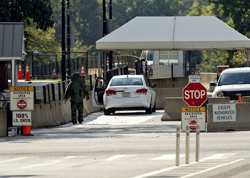 An explosive technician in a bomb suit approaches a vehicle near the entrance to White House in Washington, Saturday, Sept. 20, 2014. Secret Service says a man has been arrested for trying to unlawfully enter the White House, less than 24 hours after a fence-jumper made it all the way into the building. (AP Photo/Pablo Martinez Monsivais)