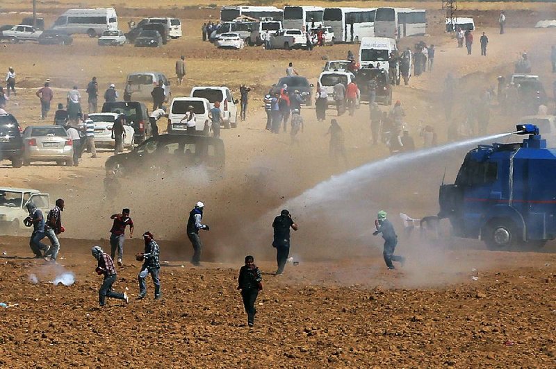 Riot police use water cannons to disperse Kurdish demonstrators who were clashing with Turkish security forces, as thousands of Syrian refugees continue to arrive at the border in Suruc, Turkey, Monday, Sept. 22, 2014. Turkey opened its border Saturday to allow in up to 60,000 people who massed on the Turkey-Syria border, fleeing the Islamic militants’ advance on Kobani.(AP Photo/Burhan Ozbilici)