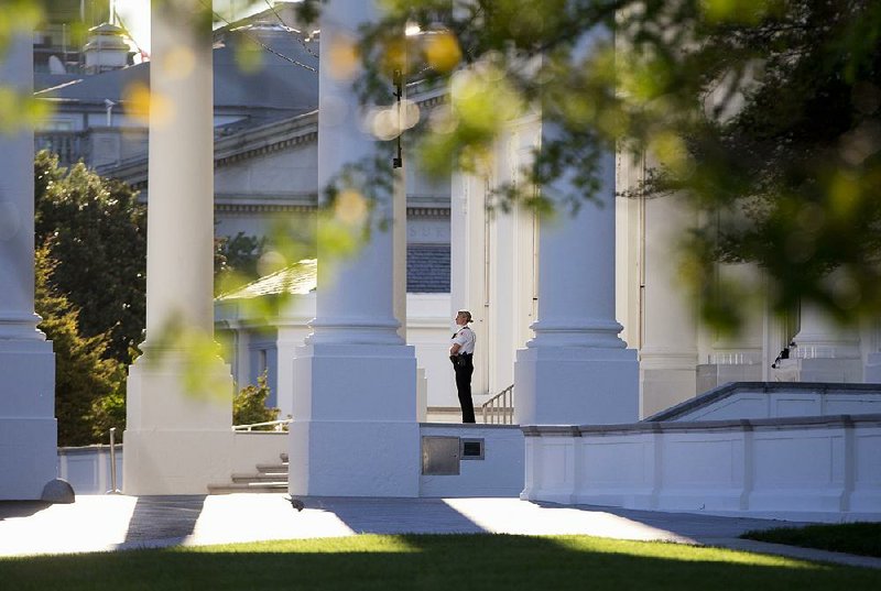 A member of the Secret Service Uniformed Division looks out from the North Portico of the White House in Washington, Monday, Sept. 22, 2014. The Secret Service tightened their guard outside the White House after Friday's embarrassing breach in the security of one of the most closely protected buildings in the world. A man is accused of scaling the White House perimeter fence, running across the lawn and entering the presidential mansion before agents stopped him. (AP Photo/Carolyn Kaster)