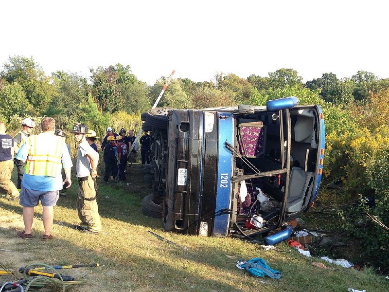 Passengers from a tour bus are treated for injuries near the overturned bus at the Tybouts Corner onramp from southbound Delaware 1 to Red Lion Road, Sunday, Sept. 21, 2014, in Bear, Del. The crash left two women dead and several other passengers injured, authorities said. (AP Photo/The Wilmington News-Journal, John J. Jankowski)
