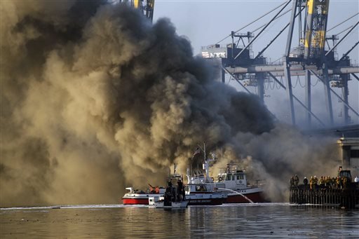 Los Angeles Firefighters watch as smoke from a dock fire rises at the Port of Los Angeles in the Wilmington section of Los Angeles on Tuesday, Sept 23, 2014. The fire that forced evacuations from the wharf continues to smolder but officials say it's under control. Nearly 12 hours after starting, the blaze is sending up huge plumes of smoke that is drifting over Los Angeles Harbor early Tuesday.