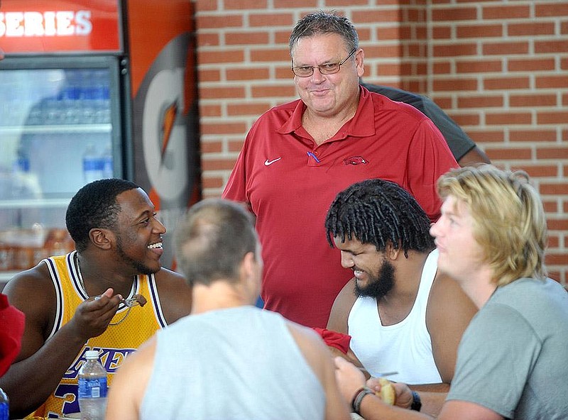 NWA Media/Michael Woods --08/03/2014-- w @NWAMICHAELW..University of Arkansas assistant coach Sam Pittman chats with linemen Cameron Jefferson (left) and Sebastian Tretola (right)  as they eat dinner after reporting for fall camp Sunday evening at the Fred Smith Center on U of A campus.