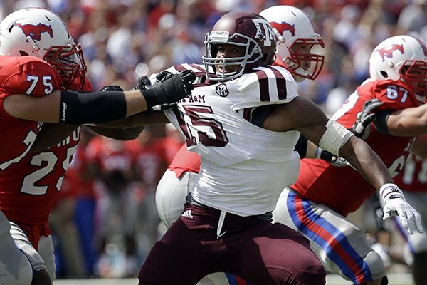 SMU offensive linesman Kris Weeks (75) and running back K.C. Nlemchi (25) fights off a rush by Texas A&M defensive lineman Myles Garrett (15) during an NCAA college football game, Saturday, Sept. 20, 2014, in Dallas. (AP Photo/Tony Gutierrez)