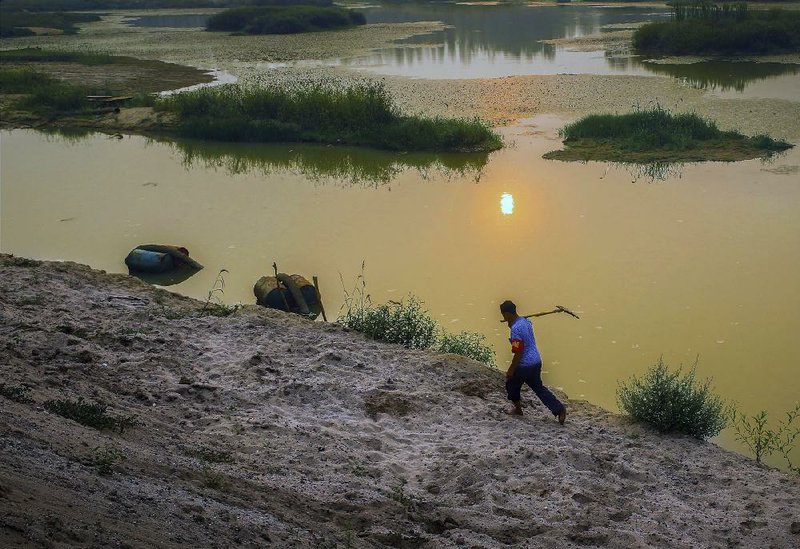 A farmer walks by a river where the sandbars can easily be seen in the low water of Pingdingshan in central China’s Henan province in mid-August.