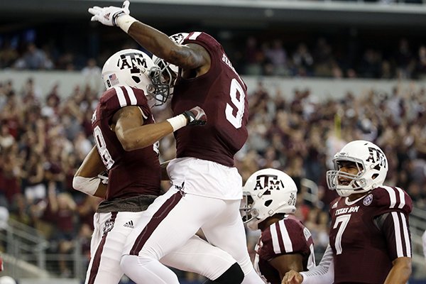 Texas A&M wide receiver Edward Pope, left, celebrates with Ricky Seals-Jones (9) and Kenny Hill (7) after Pope grabbed a pass from Hill for a touchdown against Arkansas in the first half of an NCAA college football game, Saturday, Sept. 27, 2014, in Arlington, Texas. (AP Photo/Tony Gutierrez)