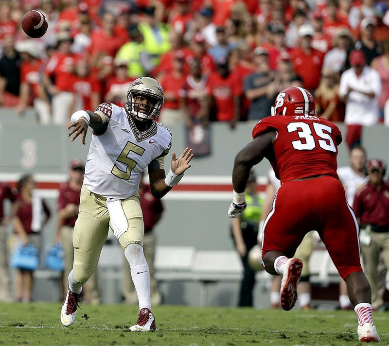 Florida State quarterback Jameis Winston (5) throws a pass as North Carolina State's Kentavius Street (35) rushes during the first half of an NCAA college football game in Raleigh, N.C., Saturday, Sept. 27, 2014. (AP Photo/Gerry Broome)