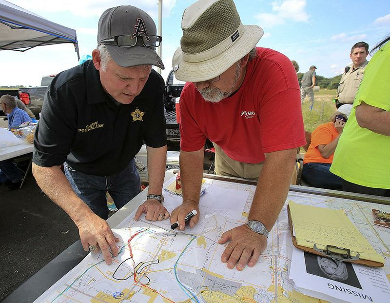 Pulaski County Sheriff Doc Holladay (left) and David Goldstein locate areas on Faulkner Lake Road for volunteers to search for missing real estate agent Beverly Carter, 49. Volunteers gathered Saturday to help search for Carter, who has been missing since Thursday evening.