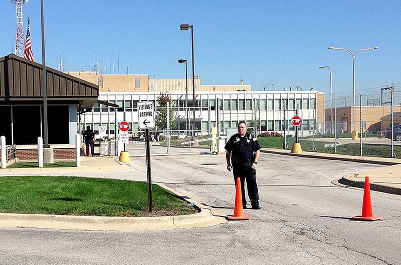 A security officer guards the front of the air traffic control facility Friday in Aurora, Ill., where a fire resulted in thousands of canceled and delayed flights.