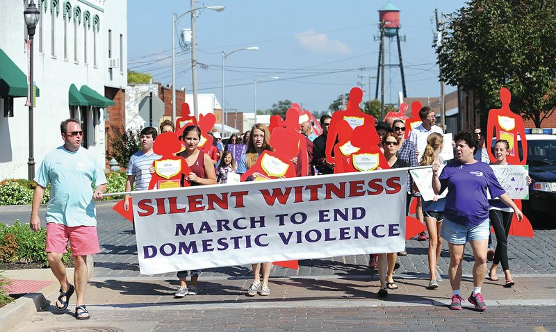 STAFF PHOTO ANDY SHUPE Marchers make their way down First Street with signs and silhouettes of people during the second Silent Witness walk.