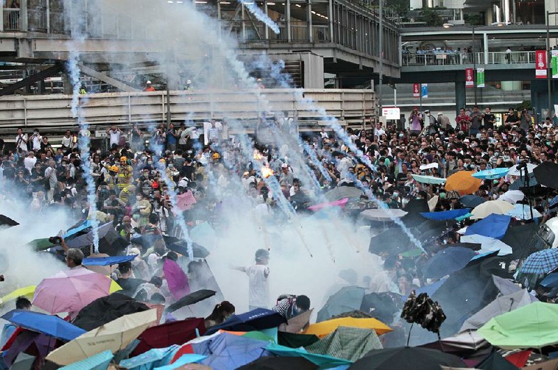 Riot police launch tear gas into the crowd as thousands of protesters surround the government headquarters in Hong Kong Sunday, Sept. 28, 2014. Hong Kong police used tear gas on Sunday and warned of further measures as they tried to clear thousands of pro-democracy protesters gathered outside government headquarters in a challenge to Beijing over its decision to restrict democratic reforms for the city. (AP Photo/Wally Santana)